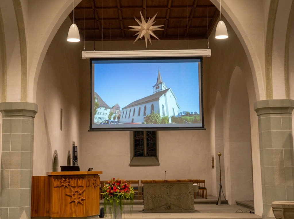 Kirche Diessenhofen – moderne Kirchenbeschallung und integrierte Projektionstechnik mit Beamerlift Innenraum der Kirche Diessenhofen mit grosser Projektionsfläche, integrierter Beamerlift‑Lösung und moderner Kirchenbeschallung; klare Sprachübertragung und flexible Multimediatechnik für Gottesdienste und Präsentationen.