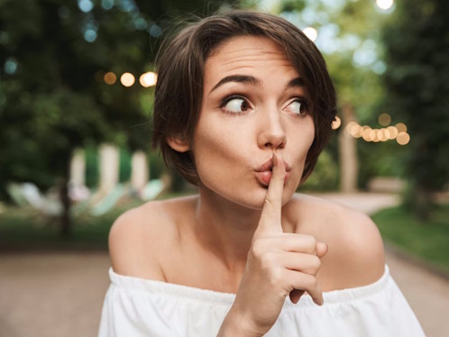 Person mit Finger‑auf‑die‑Lippen‑Geste in ruhiger Outdoor‑Atmosphäre, Symbol für lautlose Silent Partys ohne Lärmbelästigung